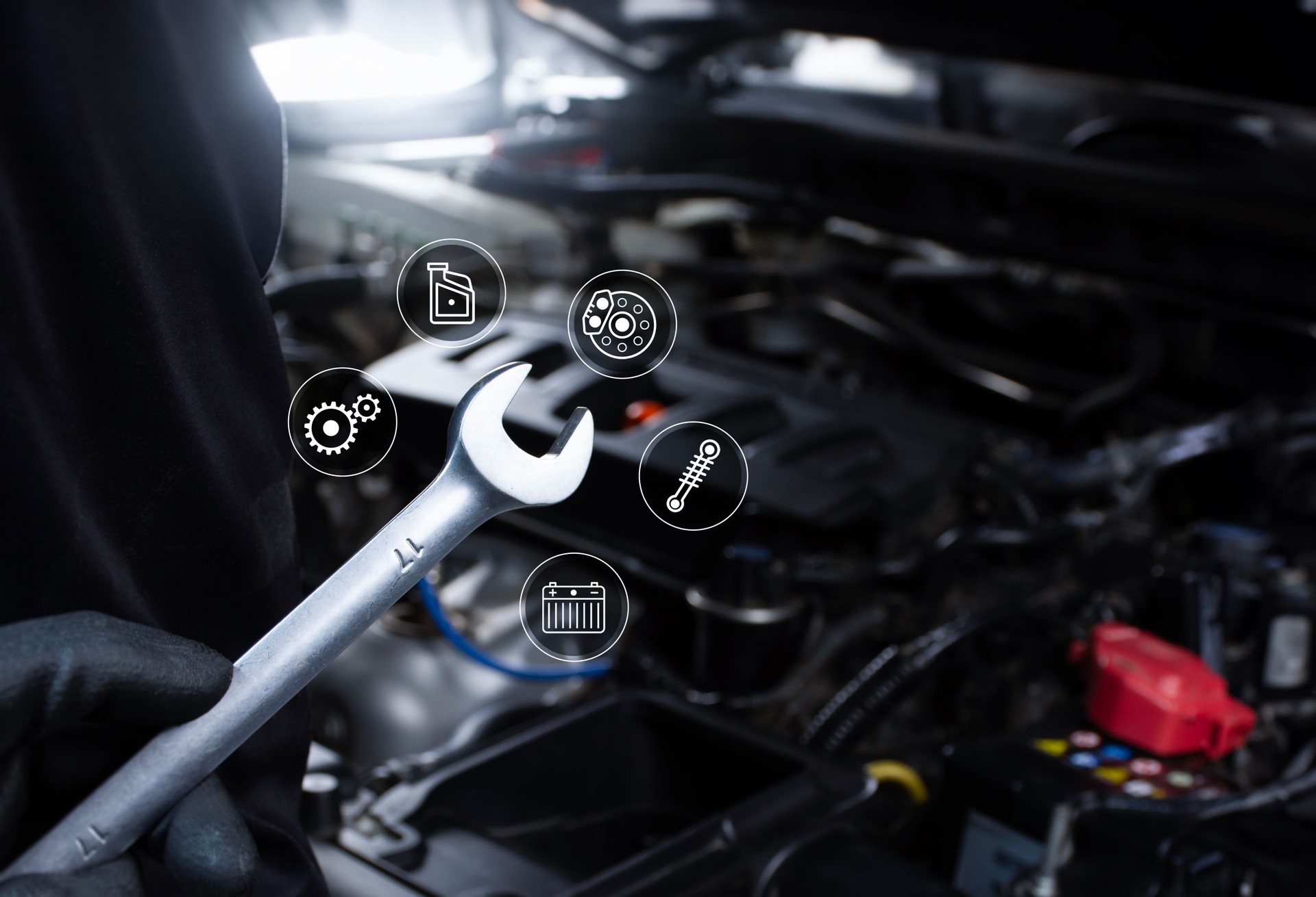 Mechanic hand holding a wrench for car repairing include an car engine blurred on background